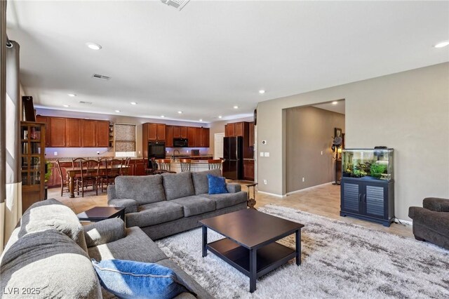living room with baseboards, visible vents, and recessed lighting