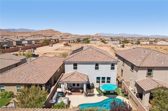 back of property featuring stucco siding, a tiled roof, a mountain view, and a residential view