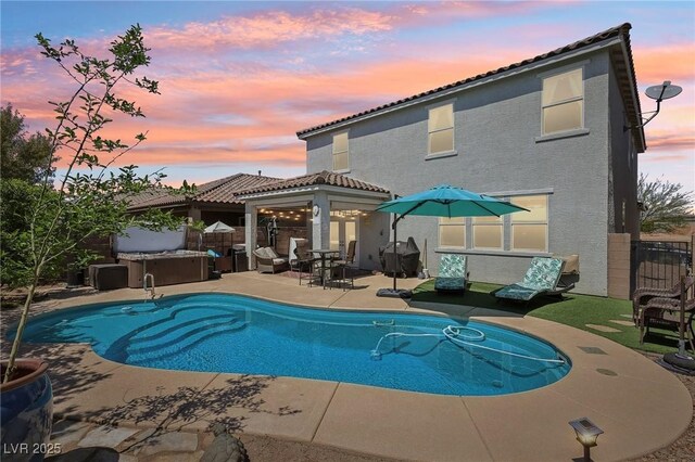 rear view of property with a patio, a fenced in pool, stucco siding, and a hot tub