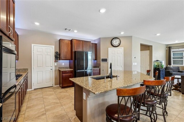 kitchen featuring a breakfast bar area, light tile patterned flooring, a sink, and freestanding refrigerator