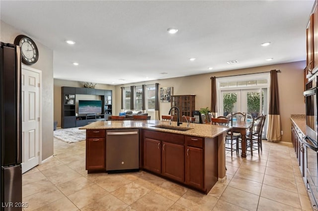 kitchen featuring recessed lighting, light stone counters, dishwasher, a sink, and french doors