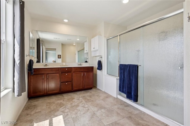 full bath with recessed lighting, a shower stall, double vanity, and a sink