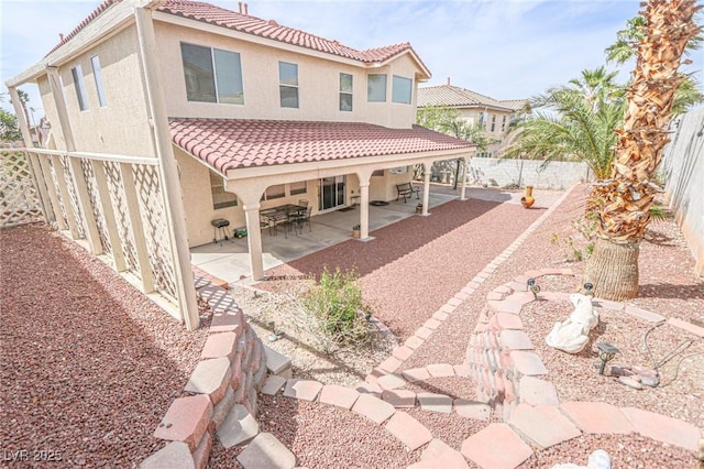 back of house featuring a patio, a tile roof, a fenced backyard, and stucco siding