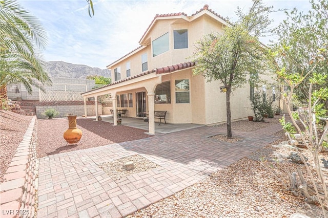 back of house with stucco siding, fence, a tiled roof, and a patio