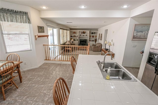 kitchen with tile counters, baseboards, recessed lighting, and a sink