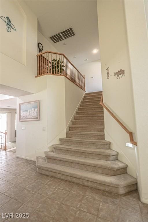 stairway with a high ceiling and visible vents
