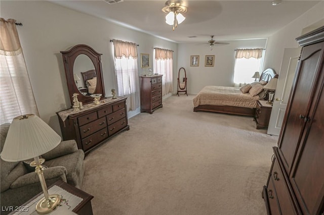 bedroom with visible vents, multiple windows, a ceiling fan, and light carpet