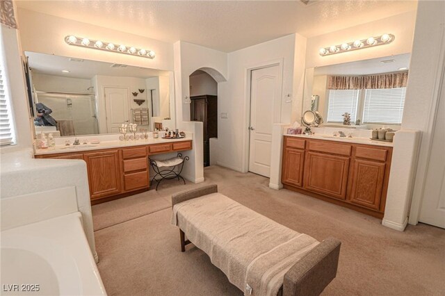 bathroom featuring two vanities, a sink, and a stall shower