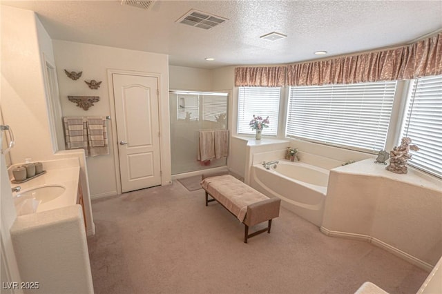 full bath featuring vanity, a textured ceiling, a stall shower, a garden tub, and visible vents