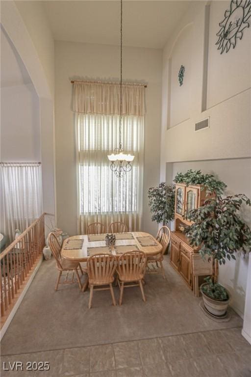 dining area featuring a towering ceiling, arched walkways, a chandelier, and visible vents