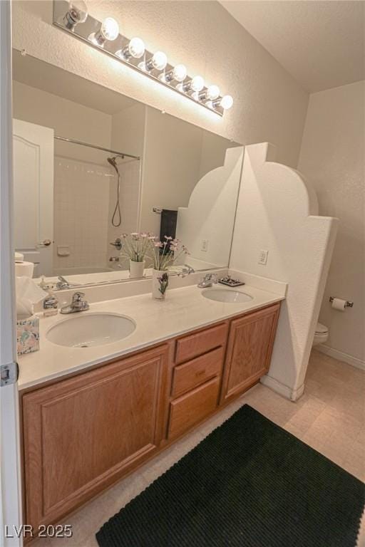 full bath featuring double vanity, toilet, a shower, and a sink