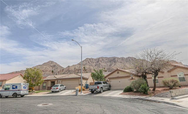 view of street featuring sidewalks, street lighting, a mountain view, and curbs