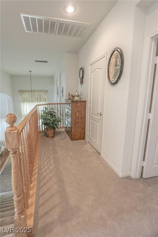 hall with baseboards, an upstairs landing, visible vents, and light colored carpet