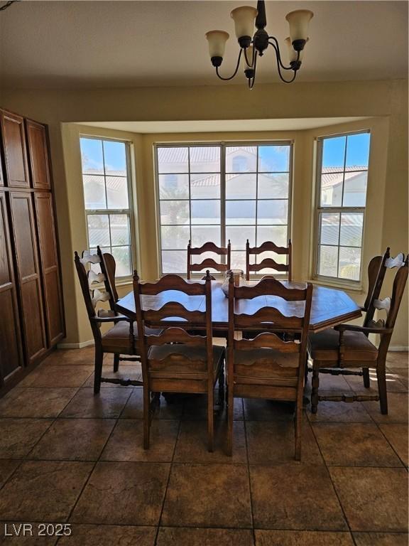 dining area featuring baseboards, a healthy amount of sunlight, and a chandelier