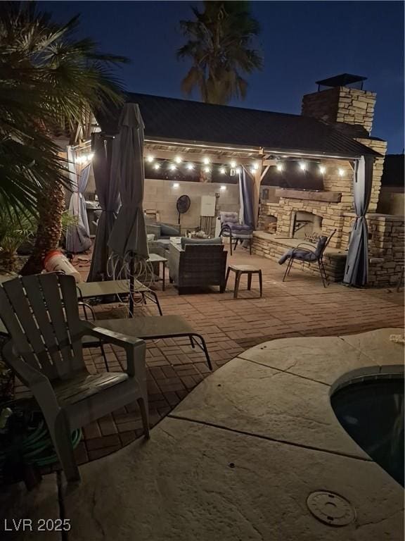 patio at twilight featuring an outdoor living space with a fireplace