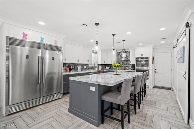 kitchen featuring a kitchen island, a kitchen bar, white cabinetry, backsplash, and stainless steel appliances