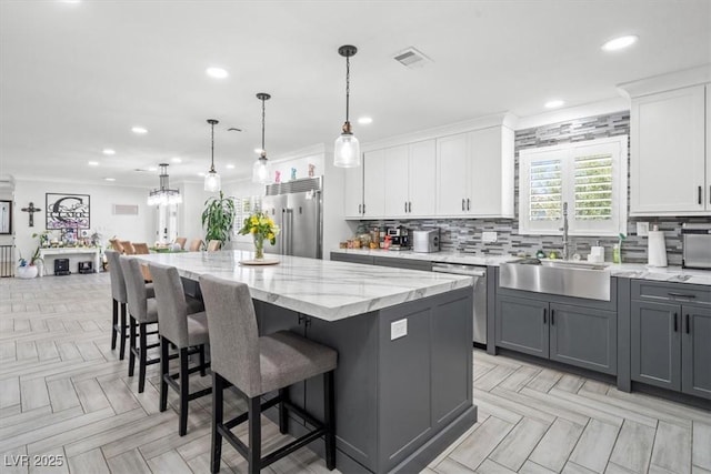 kitchen with decorative backsplash, a center island, a sink, stainless steel appliances, and white cabinetry