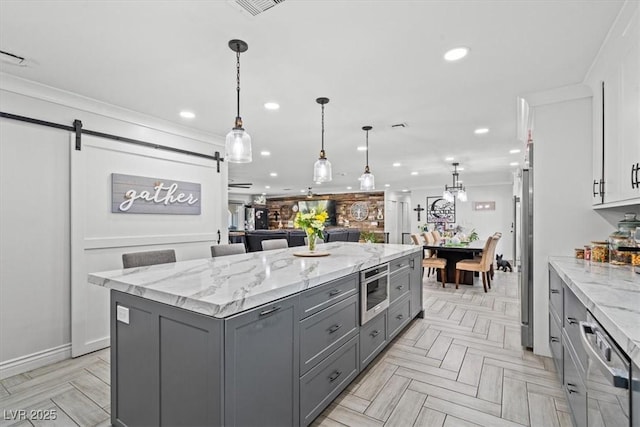 kitchen featuring a center island, a barn door, gray cabinetry, recessed lighting, and white cabinetry