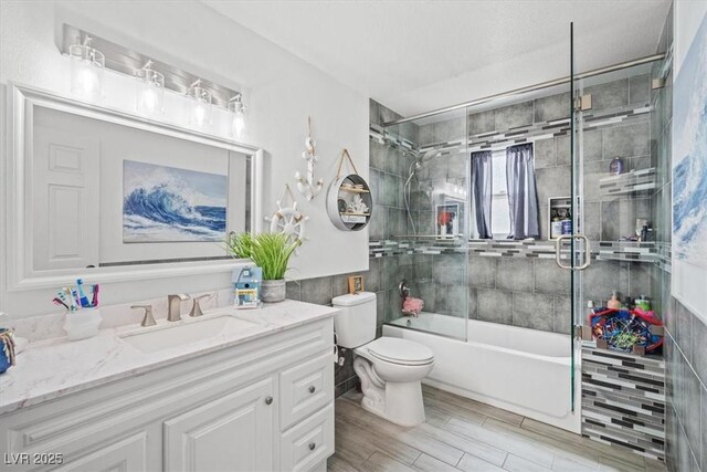 bathroom with vanity, enclosed tub / shower combo, wood finished floors, and toilet