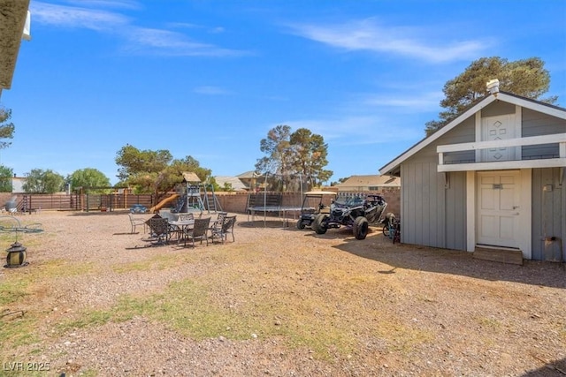 view of yard with a trampoline, a playground, and fence