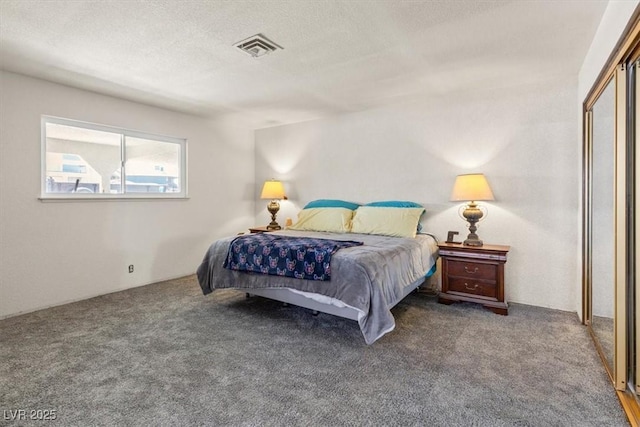 carpeted bedroom featuring a textured ceiling and visible vents