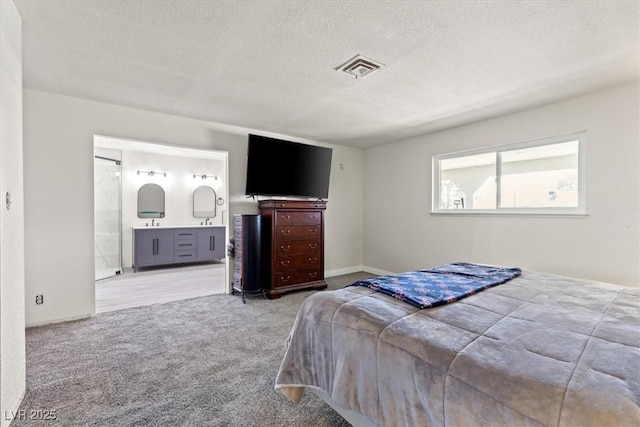 bedroom featuring connected bathroom, a textured ceiling, visible vents, and carpet