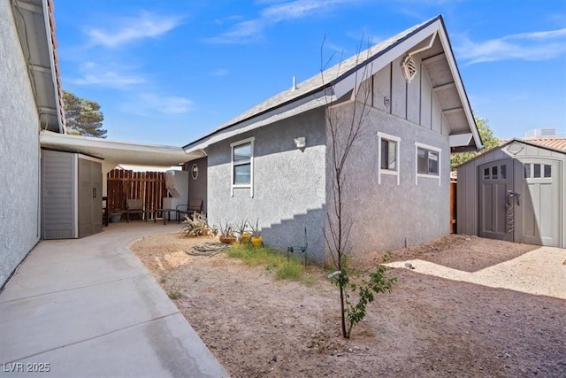 view of property exterior with a storage shed, an outdoor structure, a patio area, and stucco siding