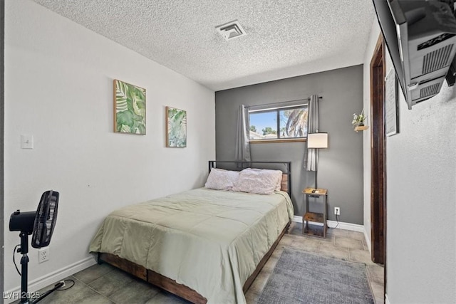 bedroom featuring a textured ceiling, visible vents, and baseboards