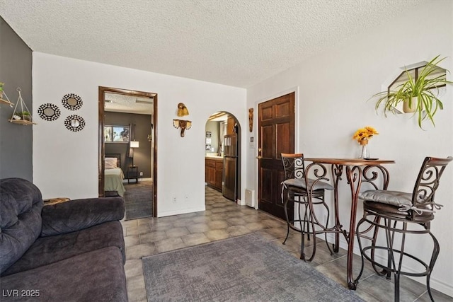 living room with arched walkways and a textured ceiling