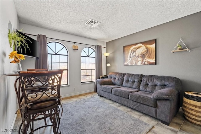 living room with baseboards, a textured ceiling, and visible vents