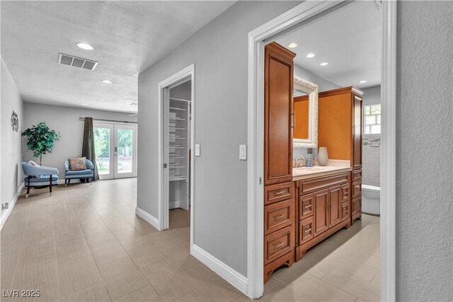 4678 Saddle Pl, Las Vegas, NV 89119 - hall with french doors, recessed lighting, a textured ceiling, baseboards, and a sink