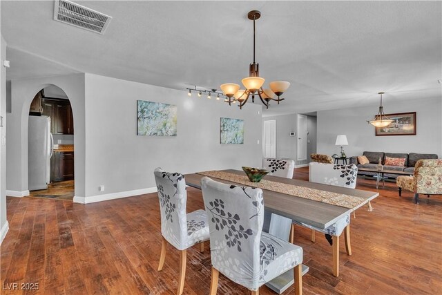 4678 Saddle Pl, Las Vegas, NV 89119 - dining space featuring a chandelier, arched walkways, wood finished floors, baseboards, and rail lighting