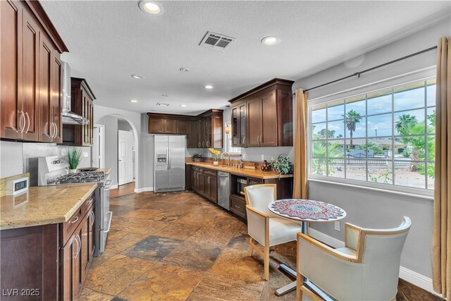 4678 Saddle Pl, Las Vegas, NV 89119 - kitchen with stainless steel appliances, arched walkways, baseboards, recessed lighting, and dark brown cabinets