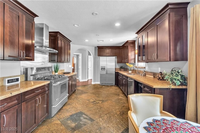 4678 Saddle Pl, Las Vegas, NV 89119 - kitchen with appliances with stainless steel finishes, wall chimney exhaust hood, arched walkways, dark stone finish floors, and recessed lighting