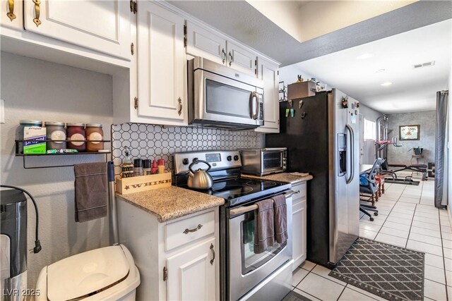 4678 Saddle Pl, Las Vegas, NV 89119 - kitchen featuring appliances with stainless steel finishes, light tile patterned flooring, decorative backsplash, white cabinets, and recessed lighting