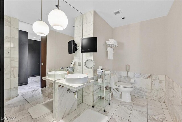 4381 W Flamingo Rd Unit 1609, Las Vegas, NV 89103 - bathroom with tile walls, toilet, marble finish floor, a sink, and visible vents