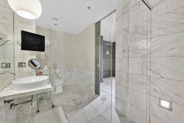 4381 W Flamingo Rd Unit 1609, Las Vegas, NV 89103 - bathroom featuring toilet, a sink, tile walls, and visible vents