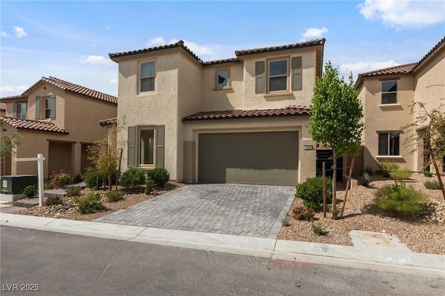 mediterranean / spanish-style house featuring stucco siding, a tiled roof, decorative driveway, and an attached garage