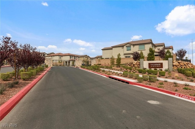 view of road featuring curbs, a residential view, a gated entry, and a gate