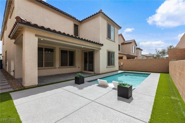 rear view of property featuring a tiled roof, a patio area, stucco siding, and a fenced backyard