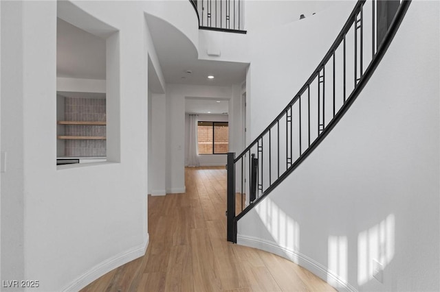 hallway featuring baseboards, recessed lighting, wood finished floors, and stairs