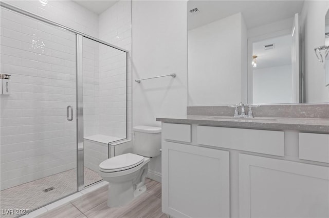 bathroom featuring visible vents, toilet, a shower stall, and vanity