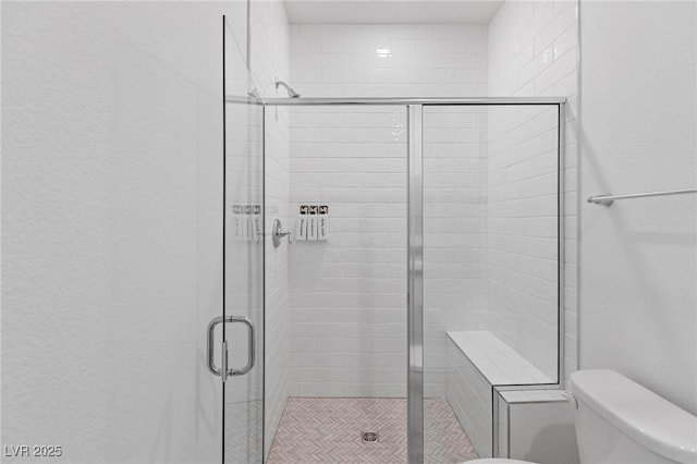 bathroom featuring toilet and a stall shower