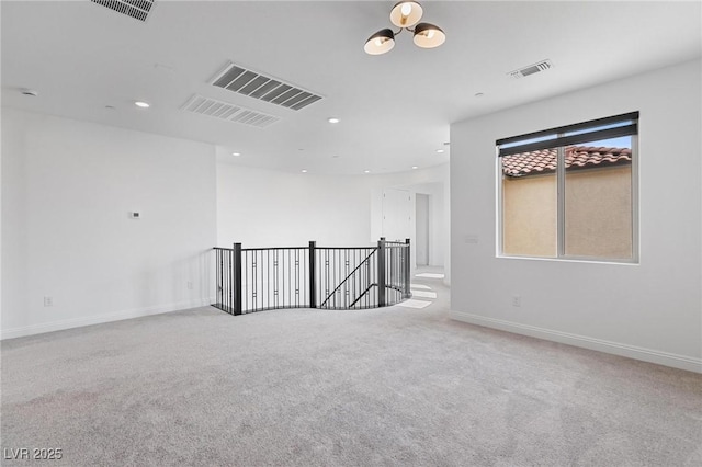 unfurnished room with carpet, visible vents, and baseboards