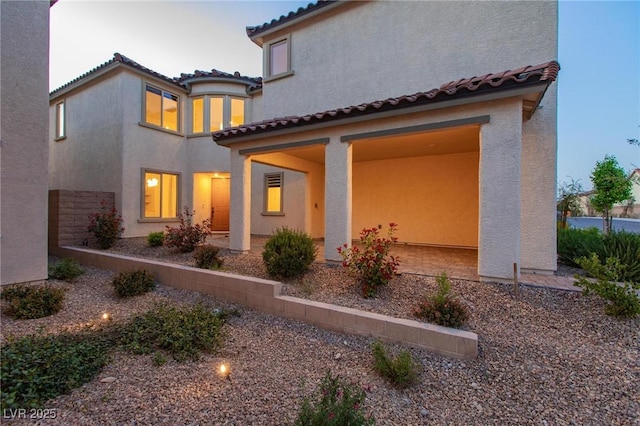 rear view of property featuring stucco siding and a tile roof