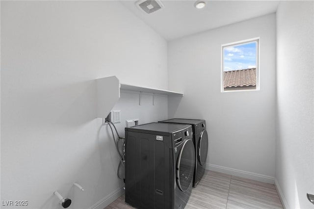 washroom featuring visible vents, baseboards, washing machine and dryer, and laundry area
