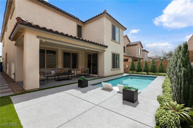 rear view of house with a patio area, a tiled roof, outdoor lounge area, fence, and stucco siding