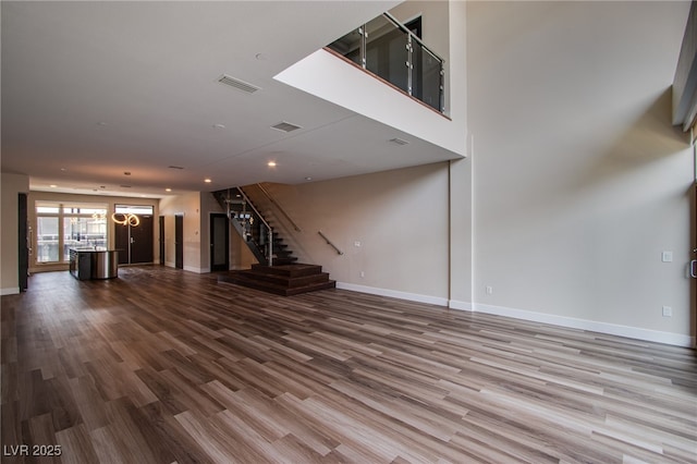 8925 W Flamingo Rd Unit 228, Las Vegas, NV 89147 - unfurnished living room featuring baseboards, visible vents, stairway, and dark wood-style flooring