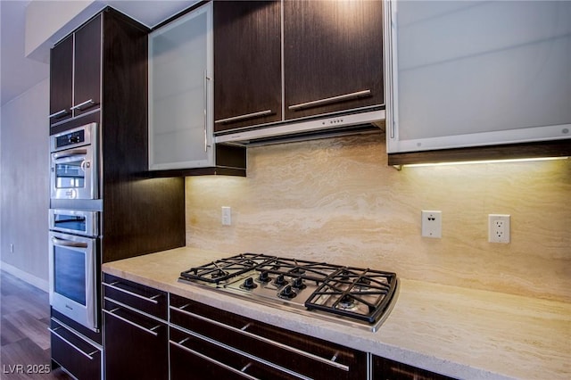 8925 W Flamingo Rd Unit 228, Las Vegas, NV 89147 - kitchen featuring backsplash, dark brown cabinetry, under cabinet range hood, and appliances with stainless steel finishes