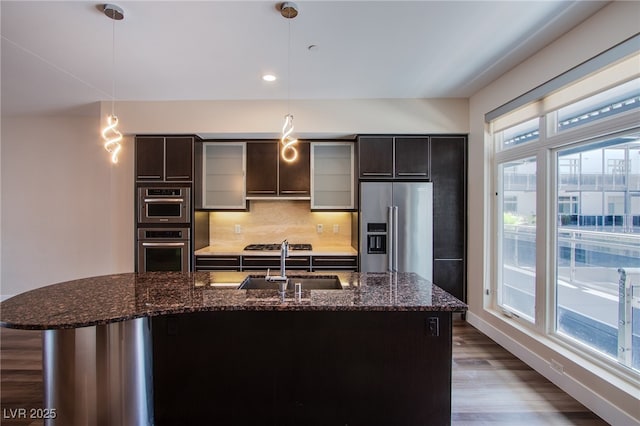 8925 W Flamingo Rd Unit 228, Las Vegas, NV 89147 - kitchen featuring backsplash, a sink, dark wood-style floors, an island with sink, and appliances with stainless steel finishes